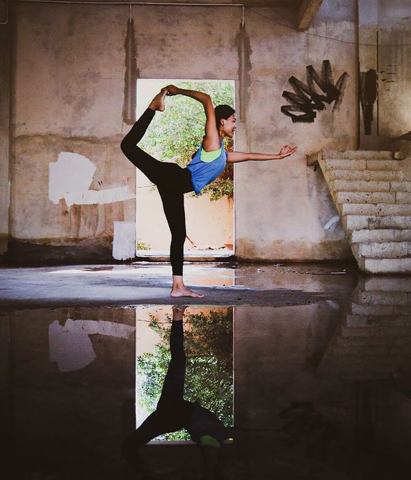 Woman in a calm yoga pose in a dark room with teal light.
